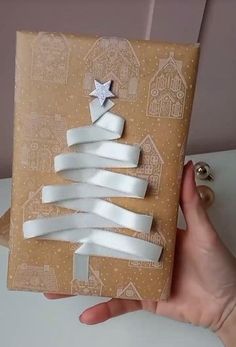 a person holding up a wrapped present with white ribbon and a star on the top