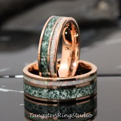 two wedding bands with green and white marble inlays on top of each other