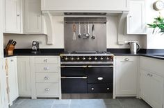 a kitchen with white cabinets and black counter tops is pictured in this image, there are utensils hanging on the wall above the stove