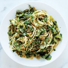 a white bowl filled with pasta covered in broccoli and sauce on top of a marble counter