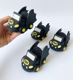 a hand is holding three small black and yellow toy cars that look like batmobiles