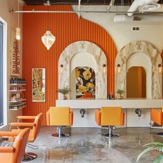 an orange and white salon with lots of chairs in front of the counter, mirrors on the wall