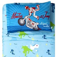 an image of a bed with blue sheets and cartoon characters on it, including a motorbike