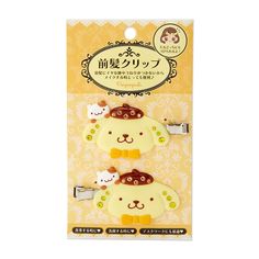 two yellow and white animal shaped hair clips in front of a card with japanese characters on it