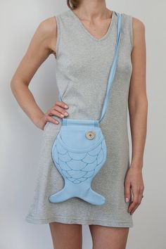 a woman wearing a blue purse with an image of a fish on it