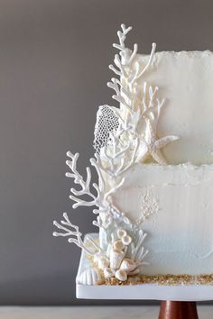 a white wedding cake decorated with corals and seashells