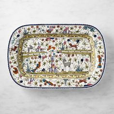 a decorative tray with animals and flowers on it, sitting on a marble surface in front of a white wall