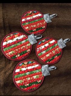 three red and green christmas ornament hanging on a brown blanket with silver metal clips