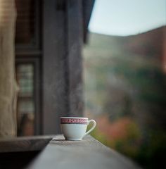 a coffee cup sitting on top of a wooden table next to a window sill