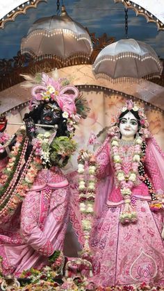 two women dressed in pink and white are standing next to each other with flowers on their heads