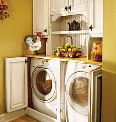 a white washer sitting inside of a kitchen next to a dryer and cabinets