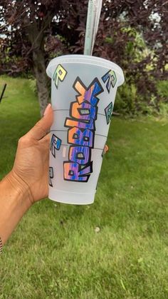 someone holding up a cup with graffiti on it