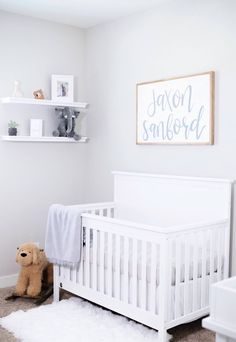 a baby's room with a white crib and teddy bear on the floor