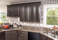 a kitchen with black and white checkered walls, granite counter tops and dark wood cabinets