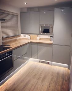 an empty kitchen with wood floors and stainless steel appliances in the middle of the room