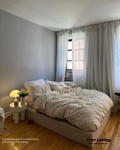 a bed sitting in the middle of a bedroom next to a window with curtains on it