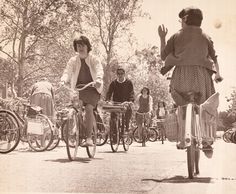 an old photo of people riding bicycles in the street and waving to someone on their bike