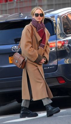 a woman walking down the street wearing a coat and scarf