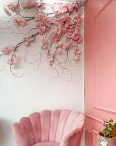 a pink chair sitting in front of a wall with flowers on it