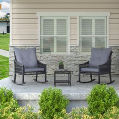 two chairs and a table sitting on the front step of a house next to bushes