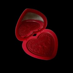 two red heart shaped boxes sitting on top of a black surface with the lid open