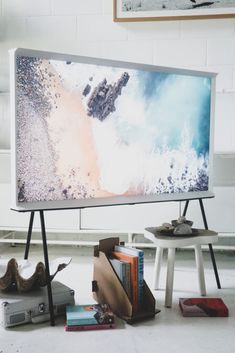 a flat screen tv sitting on top of a white table next to a book shelf