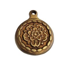 an antique brass tone pendant with a flower design on the front and back of it