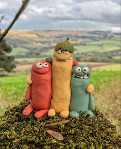 three clay figures are sitting on top of moss