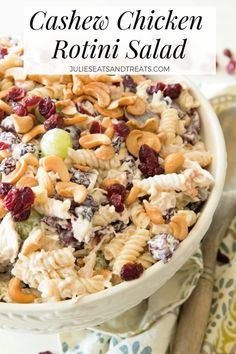 a white bowl filled with pasta salad and topped with nuts, cranberries and grapes