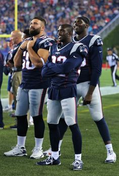 two football players standing on the sidelines with their arms around each other in front of an audience