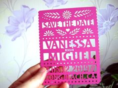 a person holding up a pink card with the word save the date printed on it