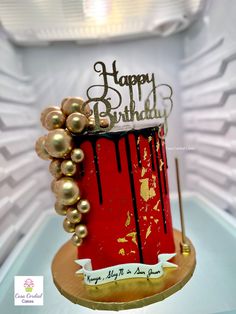 a red and gold birthday cake sitting on top of a table