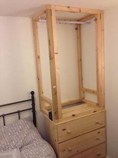 a bed with a wooden dresser next to it and a white wall in the background