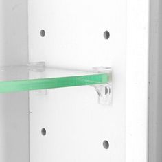 a green toothbrush is hanging on the wall next to a white shelf with holes in it