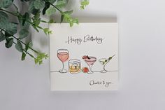 a happy birthday card with glasses of wine and fruit on the table next to it