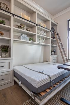 a bed with a mattress on top of it in front of a book shelf and window