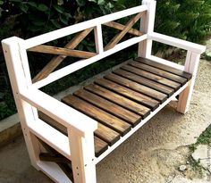 a wooden bench made out of pallets sitting on the side of a road next to bushes