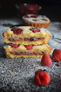 three raspberry shortcakes stacked on top of each other with fresh raspberries next to them