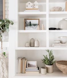 a white book shelf filled with lots of books and vases on top of it