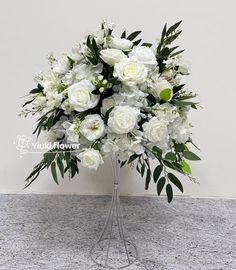 a vase filled with white flowers sitting on top of a marble counter next to a wall