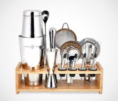 an assortment of kitchen utensils are displayed on a wooden tray with metal cups and saucers