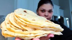 a woman holding a stack of tortillas in her hands