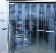 several barrels are stacked in front of a large glass door that is open to reveal the contents inside