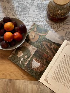 an open book and bowl of fruit on a table