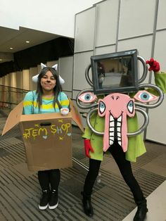 two girls dressed in costumes holding cardboard boxes with an elephant and cat on it's head