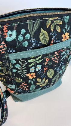 the inside of a purse with flowers and leaves on it, sitting on a white surface