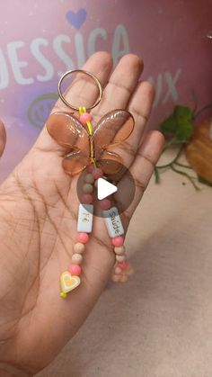 a hand holding a keychain with a flower on it's thumb and beads