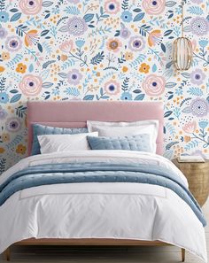 a bedroom with floral wallpaper and bedding in blue, pink, yellow and white