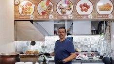 a man standing in front of a counter with plates on the wall behind him and an oven