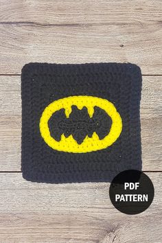 a crocheted batman symbol is shown on a wooden surface